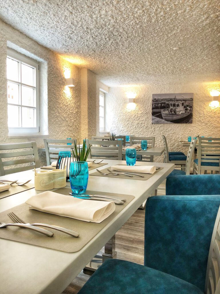 Gedeckter Tisch im hellen Fensterbereich der Taverna Korfu in Marburg mit blauen Akzenten und mediterranem Flair